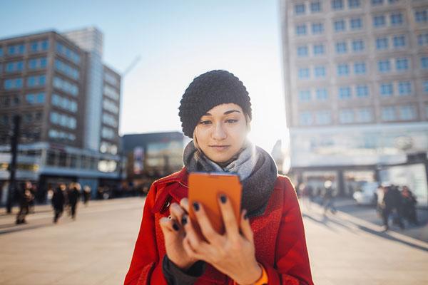 Woman In Red Coat Looking At Phone