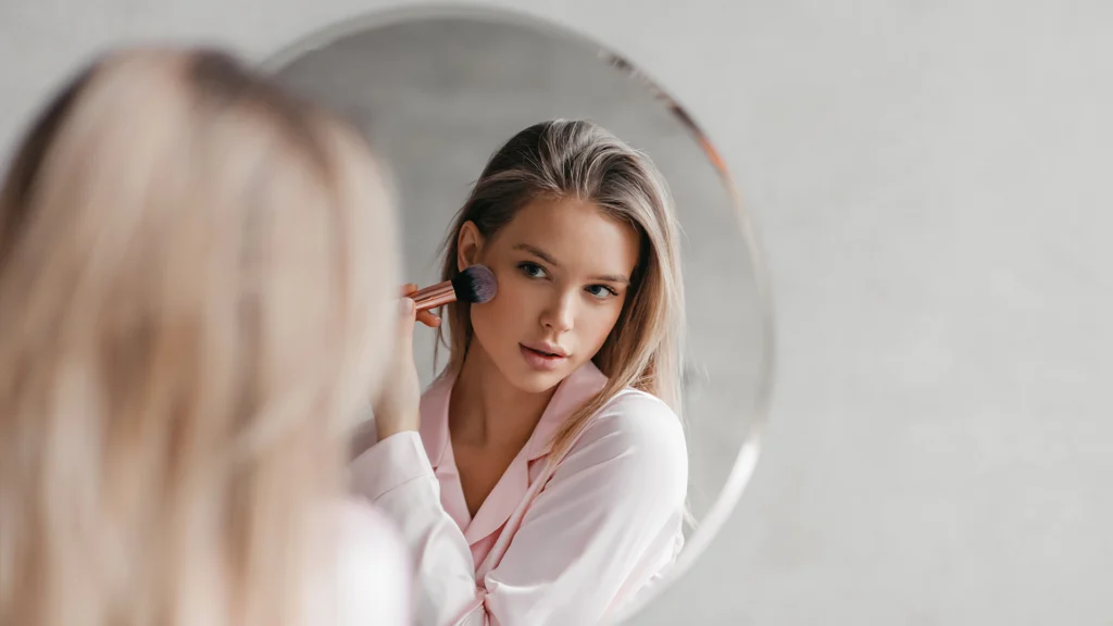 woman applying makeup in mirror