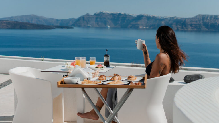A hotel guest having breakfast on a terrace overlooking the sea.